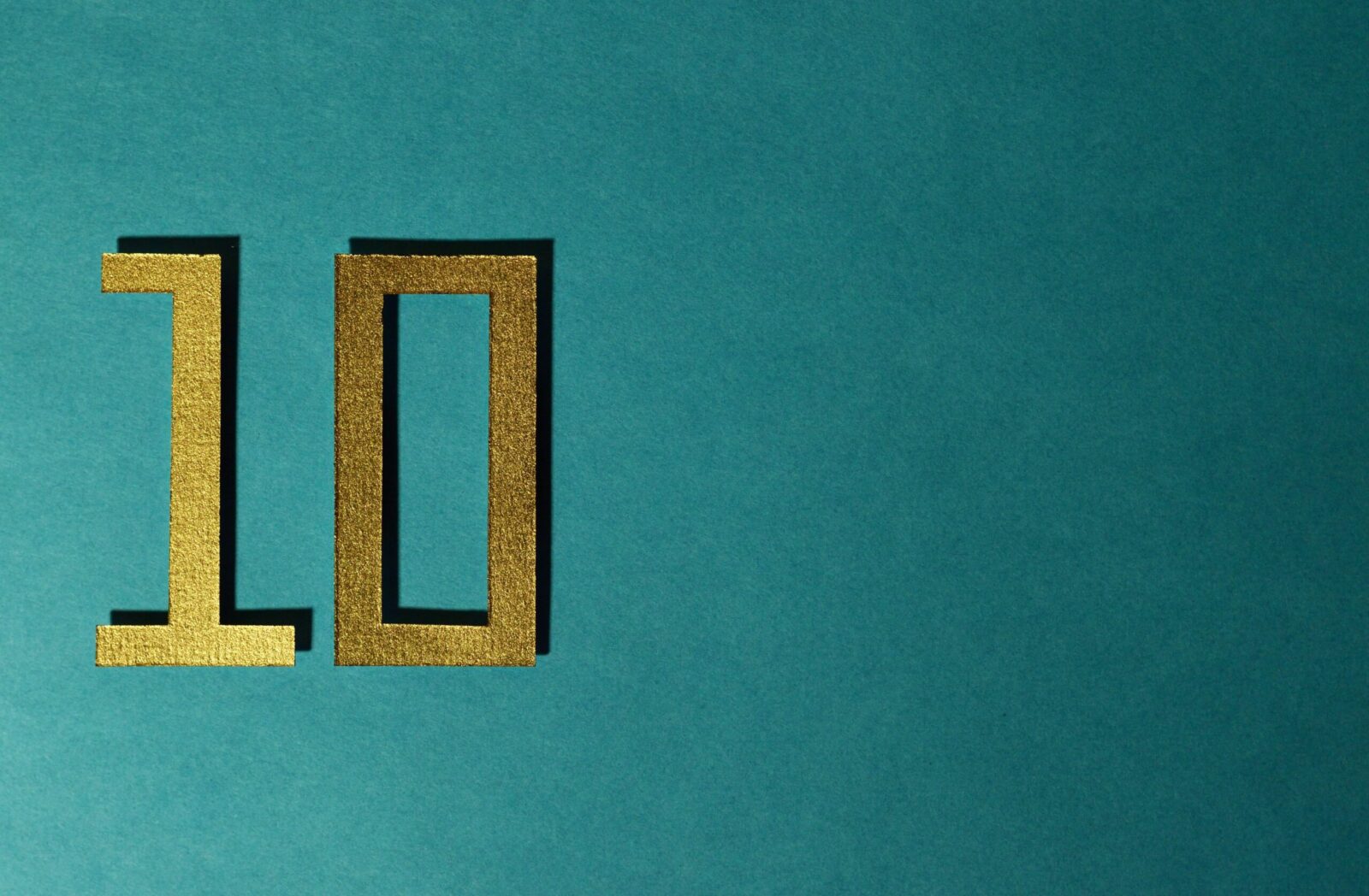 Stylish gold number ten on a textured teal background for design concepts.